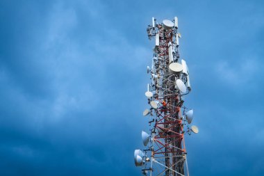 Telecommunication tower against cloudy blue sky. Copy space.