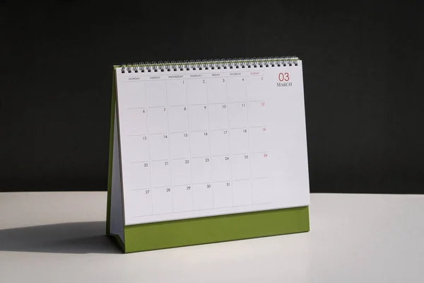 Standing desk calendar March on white table and black background.