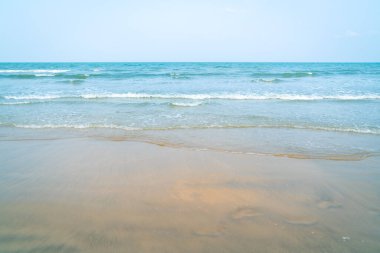 Tropik plaj ve deniz manzarası. Gün batımı, yumuşak kumda turuncu renk yansıması. Sakin sahne.