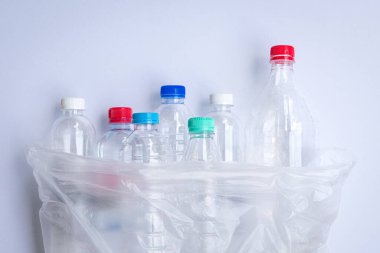 Plastik bir torba içinde plastik şişeler. Beyaz arkaplanda.