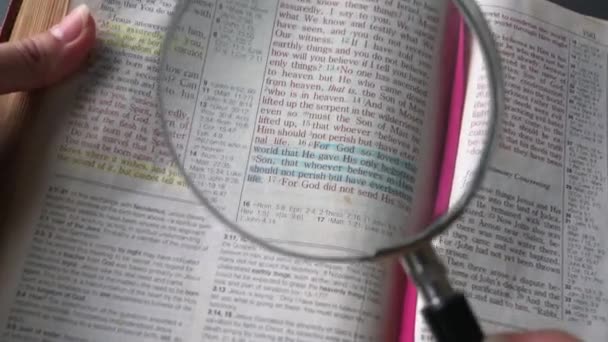 Używając Szkła Powiększającego Aby Przybliżyć Fragment Jana Nowego Testamentu Biblii — Wideo stockowe