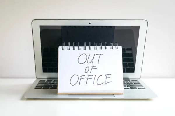 Out of office, written message on top of computer laptop.