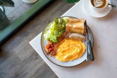 Pastırma, sosis, çırpılmış yumurta, yeşil salata ve kızarmış ekmek ile İngiliz büyük kahvaltı öğünü. Üst görünüm.