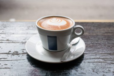 Kırsal ahşap masa üzerinde latte sanatı olan bir fincan Düz Beyaz Kahve, kaldırım kafesi. Boşluğu kopyala.