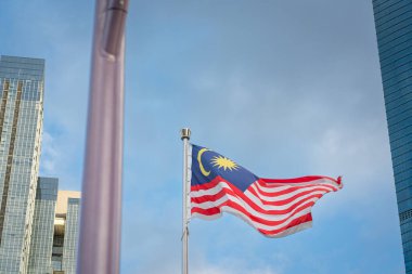 Kuala Lumpur, Malezya - 28 Ocak 2024: Kuala Lumpur şehrinde gökyüzünde dalgalanan bir direkte Malezya bayrağı