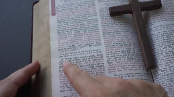 手指指向圣经经文段落 马太福音26节和最后晚餐的第26 29节 耶稣受难日 的通俗段落圣经上的一个木制十字架 — 图库视频影像