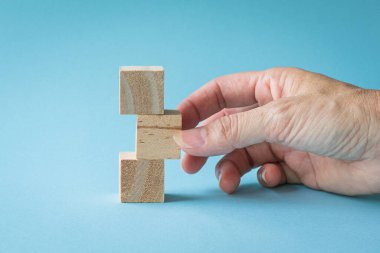 Mavi arka planda 3 boş tahta küpü dikey olarak ayarlayan kadın eli.