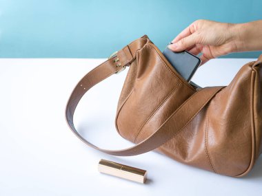 Telefonunu çantasından çıkaran kadın. Masada ruj izi var. Yaşam tarzı ya da moda konsepti.