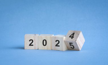 2024 'ten 2025' e kadar tahta bloklardaki rakamlar. Mavi arka plan, yeni yıl konsepti.