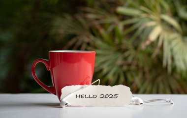 Merhaba 2025 kağıt üzerinde bir fincan kahvenin yanında. Yeni yıl kavramı.