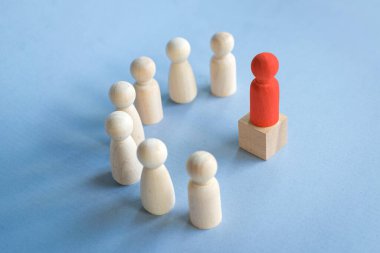 Kürsüde duran kırmızı oyuncak bloğu diğer oyuncak bloklarına bakıyor. Masanın üstünde yarı daire şeklinde duruyor. Liderlik kavramını yansıt.