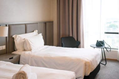 Şehre bakan beyaz yataklı ve pencereli çağdaş otel odası.