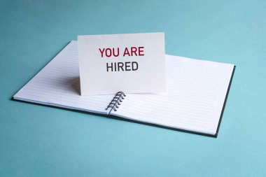 İşe alındın. Not defterinin üstündeki beyaz kartla yazılmış bir mesaj. Yeni iş ya da istihdam kavramı.