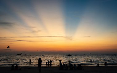 Langkawi, Malaysia - January 2, 2025: Tourists enjoying a stunning sunset at Pantai Cenang beach, the most popular beach spot at Langkawi. clipart