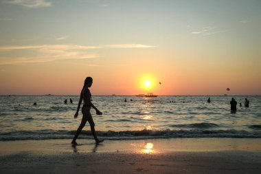 Langkawi, Malaysia - January 2, 2025: People swimming and enjoying a stunning sunset at Pantai Cenang beach, the most popular beach spot at Langkawi. clipart