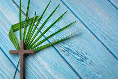 Çarmıh haçı ve ahşap masa üzerinde palmiye yaprağı. Uzayı kopyala Paskalya kutlaması kavramı.