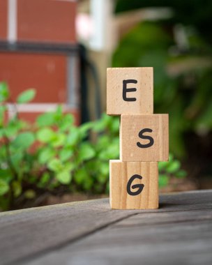 Dağıtılmış ahşap bloklar ve yeşil bitkiler hakkında ESG kelimesi.