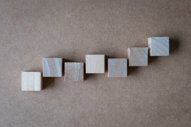 Yedi boş kare tahta blok düz arka planda düz olmayan bir yönde ilerliyor. Üst görünüm.