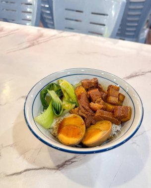 Bir kase pilav, haşlanmış domuz göbeği ve yeşil sebzeli yumurta..