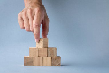 Piramidin tepesindeki boş tahta bloğu elle çevirin. Işık arkaplanında izole edilmiş, boşluğu kopyala.