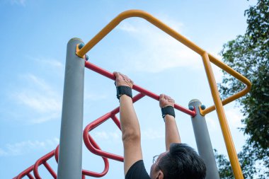 Parktaki çelik çubukta barfiks çeken bir adam. Arka plan.