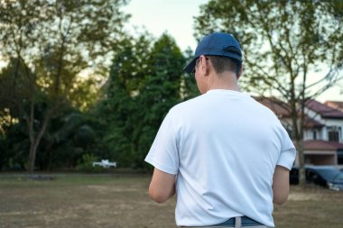 İnsansız hava aracını kontrol eden bir adam sahada duruyor..