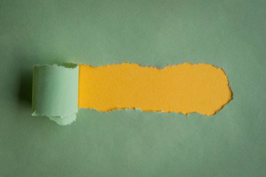 Sarı arka planda yeşil kağıtta yırtılmış bir delik. Boşluğu kopyala.