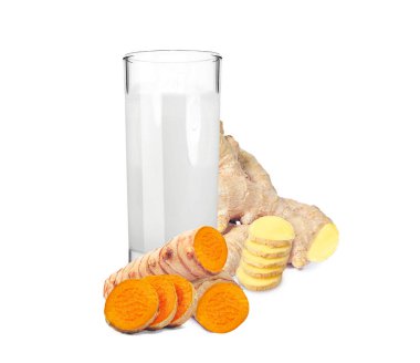 Beyaz arka planda zencefil ve zerdeçal içeren bir bardaktaki süt