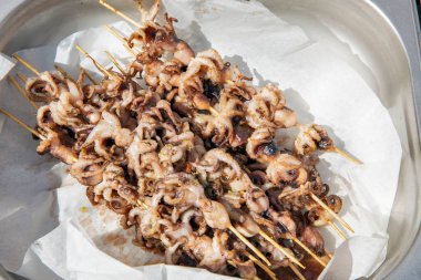 Dışarıdaki ahşap şişler üzerinde ızgara mürekkep balığı.