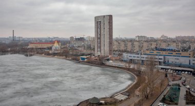 Kyiv, Ukrayna - 14 Mart 2021: Donmuş Kirillivske Gölü ve Obolon yerleşim bölgesi ile kış şehri. Endüstriyel parkı olan bir yerleşim bölgesinin bulunduğu tarihi bir bölgedir..