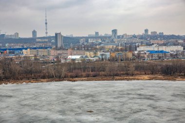 Kyiv, Ukrayna - 14 Mart 2021: Donmuş Kirillivske Gölü ve Obolon yerleşim bölgesi ile kış şehri. Endüstriyel parkı olan bir yerleşim bölgesinin bulunduğu tarihi bir bölgedir..