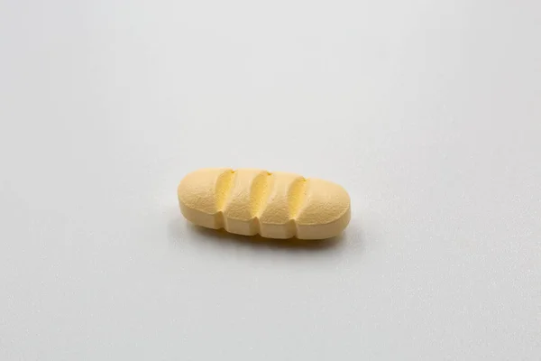 Żółta Podłużna Tabletka Paskami Rozdzielającymi Podziału Cztery Części Kolorze Białym — Zdjęcie stockowe