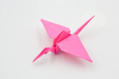 Elle toplanmış pembe kağıt turna origamisi beyaz üzerine yakın plan