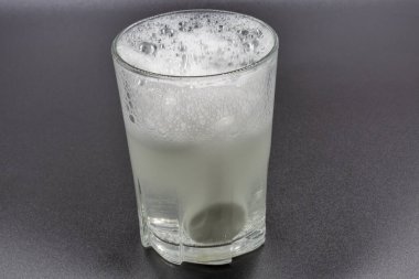 Dissolving instant effervescent tablets in a glass of water closeup on black