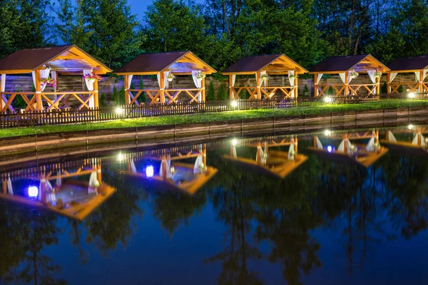 stock image Row of wooden gazebos for relaxing by the lake in the evening