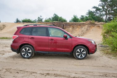 Varash, Ukrayna - 27 Haziran 2023: Kırmızı SUV Subaru Forester yağmur altında bir kum havuzunda. Subaru Forester 1997 'den beri Subaru tarafından üretilen kompakt bir geçiştir..