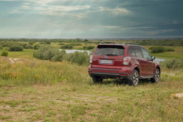 Sarny, Ukrayna - 29 Haziran 2023: kırmızı SUV Subaru Forester ile göl manzarası. Subaru Forester 1997 'den beri Subaru tarafından üretilen kompakt bir geçiştir..