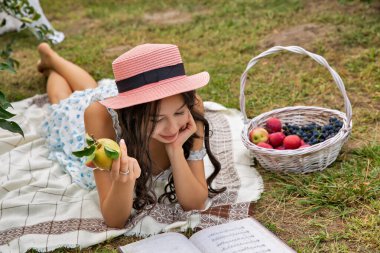 Bahçede yatan şapkalı, güzel, esmer, beyaz bir kadın..