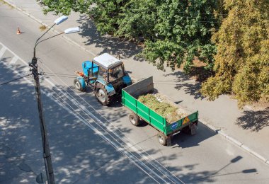 Eski traktörün sokak çöplerini temizlemek için bir karavanı var.