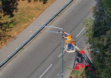 Pnömatik araba asansöründeki işçiler yeni bir sokak lambası kuruyorlar.