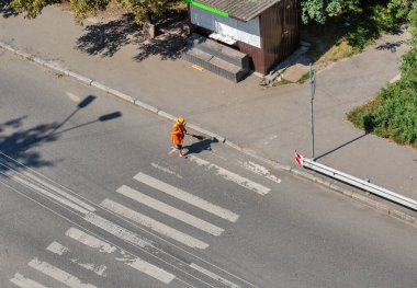 Belediye temizleyicisi elle şehir yolunu tarıyor, yukarıdan görünüyor..