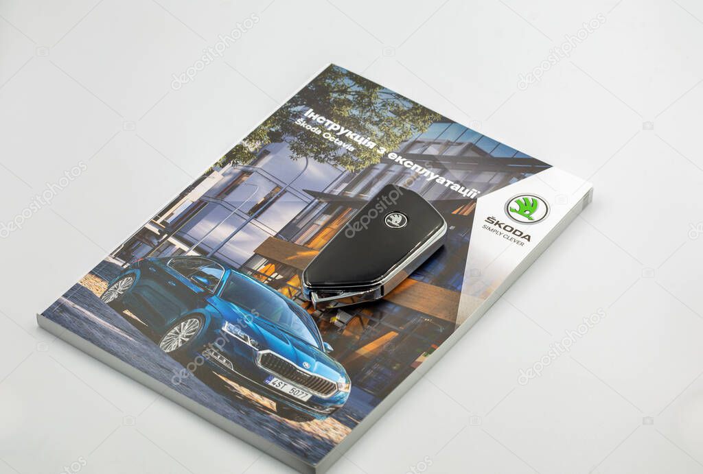 Kyiv, Ukraine - March 29, 2024: Skoda Octavia A8 operation manual with modern remote car key closeup on white. Skoda Octavia is a family car produced by the Czech manufacturer since the end of 1996.
