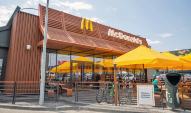 Lisniki, Kyiv, Ukrayna - 18 Mayıs 2024: Ziyaretçiler McDonald 's fast food restoranında güneş şemsiyelerinin altında açık havada yemek yiyorlar. 1940 yılında kurulan çok uluslu bir fast food zinciri..