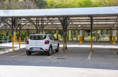 Uzhhorod, Ukrayna - 4 Nisan 2024: Beyaz Renault Sandero Stepway arabası güneş panelleriyle kaplı bir otoparka park edildi.