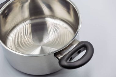 Parlak paslanmaz çelikten oluşan stüdyo çekimi. Beyaz tencereye yakın yeni tencere..