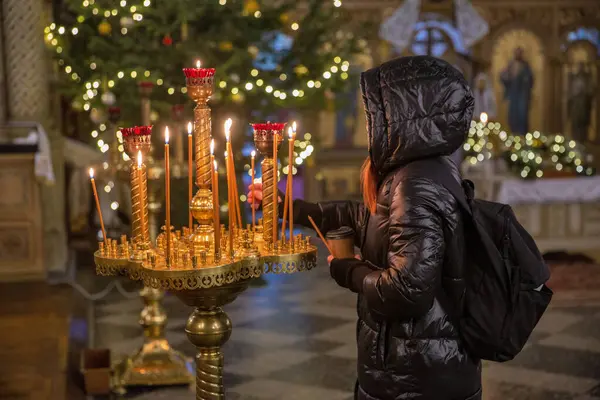 Kadın kilisede mum yakıyor. Ortodoks Kilisesi 'nde şamdan. Yakın plan. Kilisenin iç güzelliği ve huzuru..