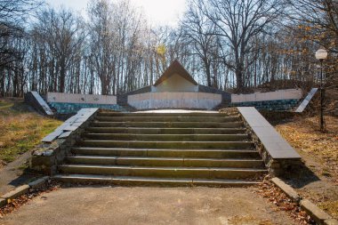 Ormanda unutulmuş bir anıt. Ormanlık alanda ihmal edilmiş bir kamu binası. Öncü kamp ateşi seremonisinin yeri..