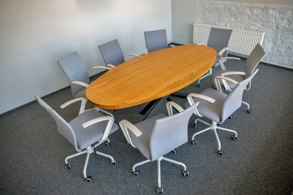 Ahşap masa ve ofis sandalyeleri olan modern boş toplantı odası.