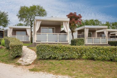 Sessiz, yeşil bir orman bölgesinde verandası olan küçük ahşap kulübeler. Etrafı ağaçlar ve yeşilliklerle çevrili olan kulübe kamp, glamping veya ekolojik yaşam temaları için idealdir..