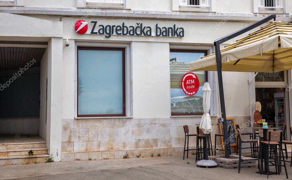 Porec, Croatia - May 21, 2025: Zagreb bank branch features a large window with an ATM inside sign, located next to a small gelateria with outdoor seating, blending financial services with local charm.